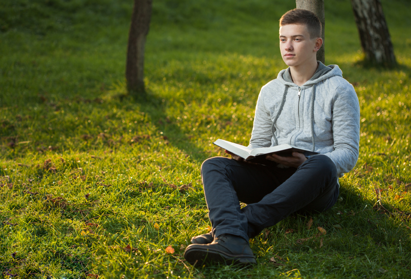 Young man reading Bible in a park